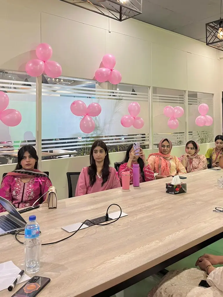 Attendees at a long conference table decorated with pink balloons