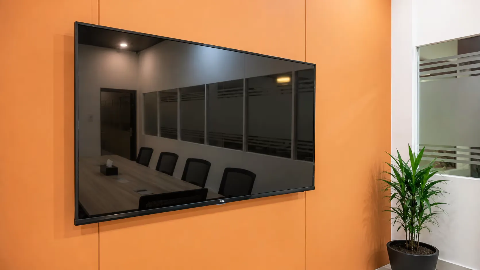A wall-mounted screen in the WorkBench meeting room, angled against the terracotta panelled wall