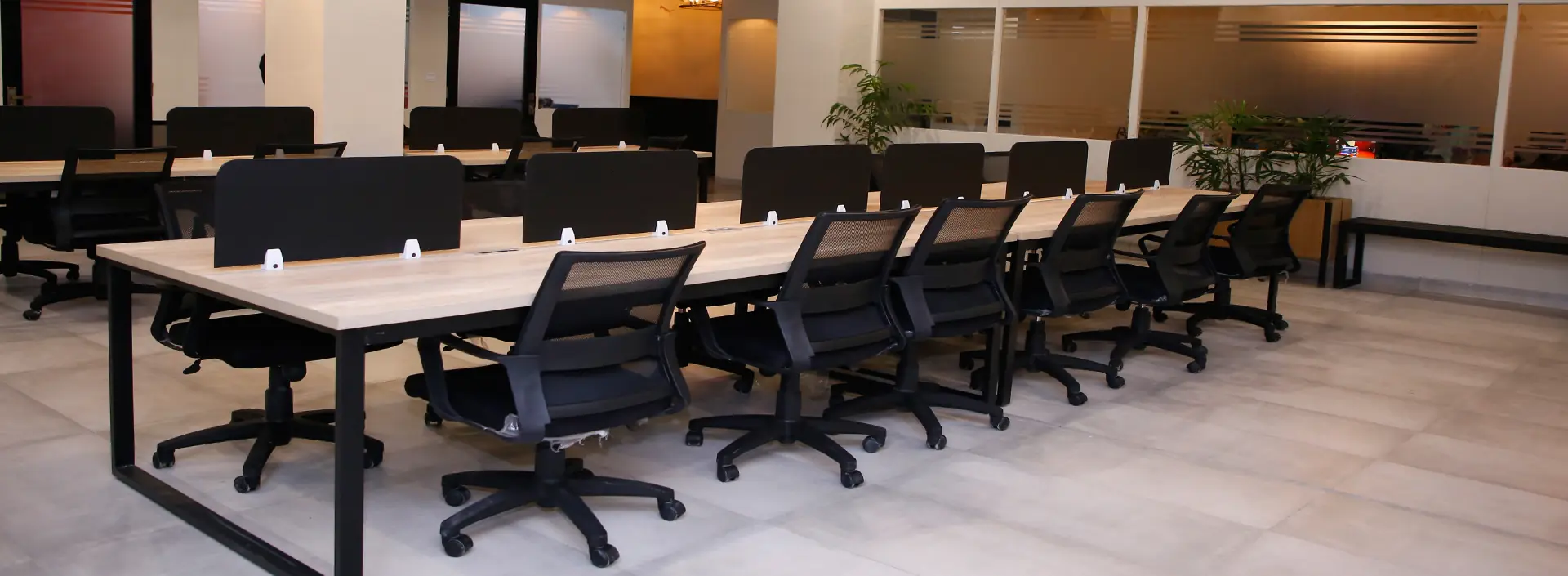 A long run of shared desks and ergonomic chairs on the open floor