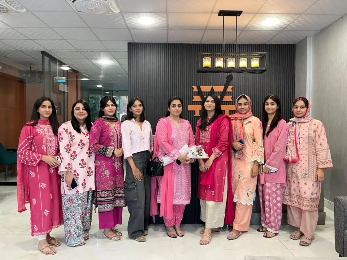 A group of guests posed together at an event hosted at WorkBench Lahore, in front of the reception's amber W logo
