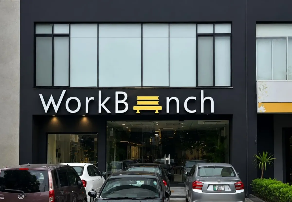 The WorkBench building on 13-D in Valencia Town, Lahore: a dark fronted building with the lit WorkBench sign above the glass entrance and cars parked in front.