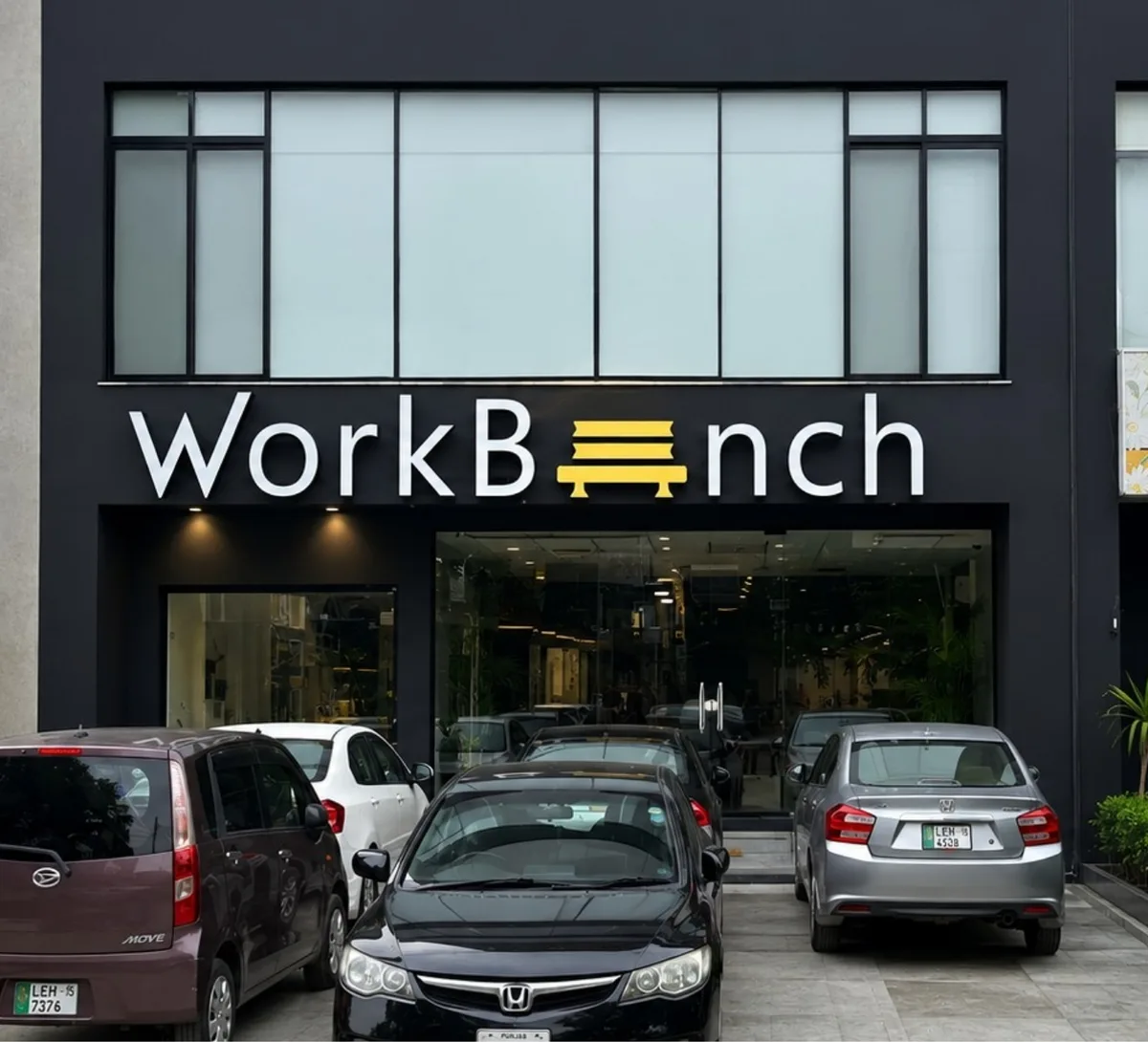 The WorkBench building on 13-D, Valencia Town: the sign above the glass entrance and cars parked in front.