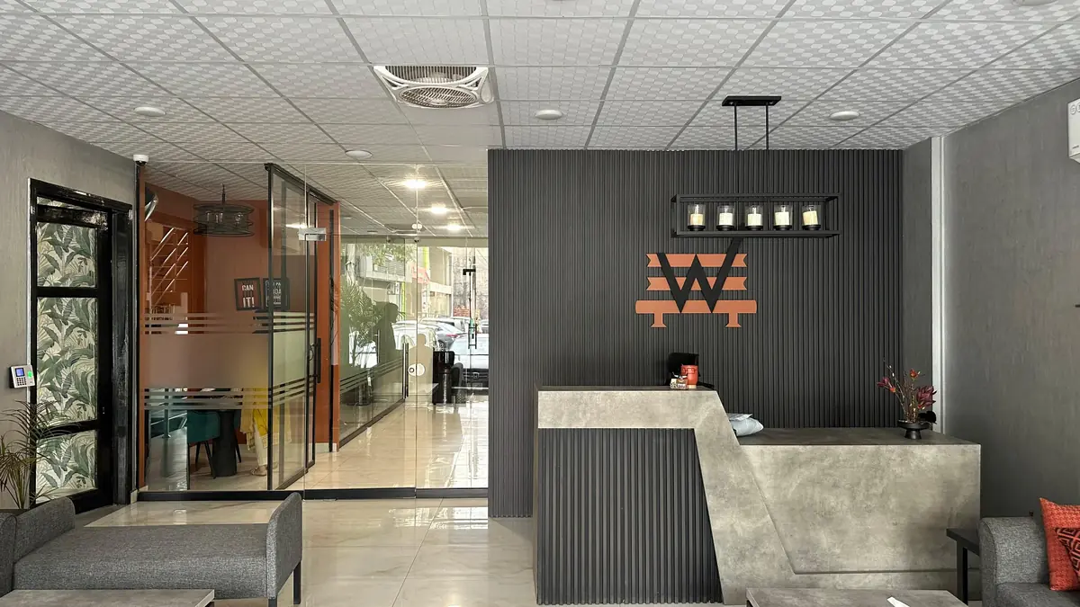 The WorkBench reception in Lahore, a charcoal fluted wall behind the desk with the amber W lit above it